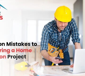 Construction worker in a yellow hard hat reviewing renovation plans on a laptop, with text on avoiding common home renovation mistakes.