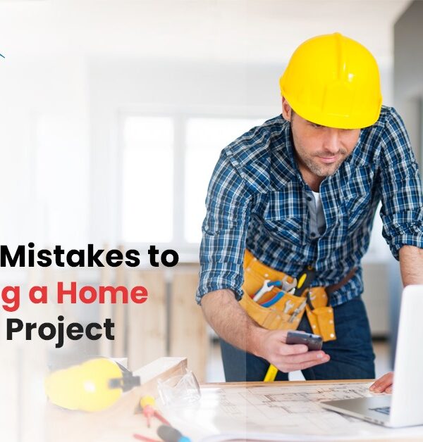 Construction worker in a yellow hard hat reviewing renovation plans on a laptop, with text on avoiding common home renovation mistakes.