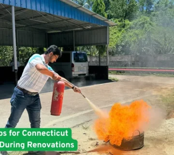 Man using fire extinguisher on open flames during a renovation safety drill outside a Connecticut home construction site now.