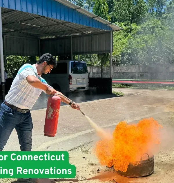 Man using fire extinguisher on open flames during a renovation safety drill outside a Connecticut home construction site now.
